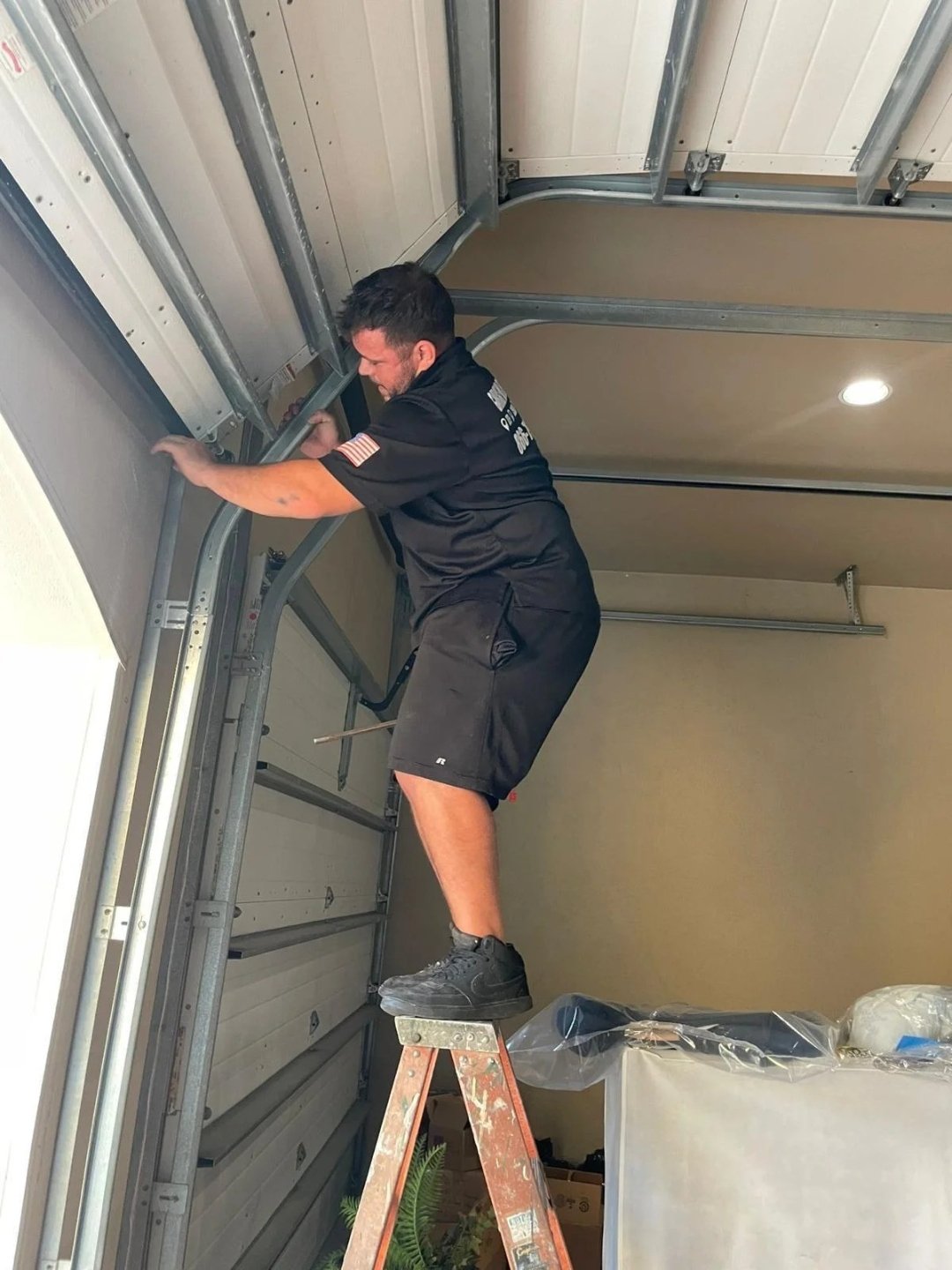 A person in a black shirt reaching up beside a curved door track
